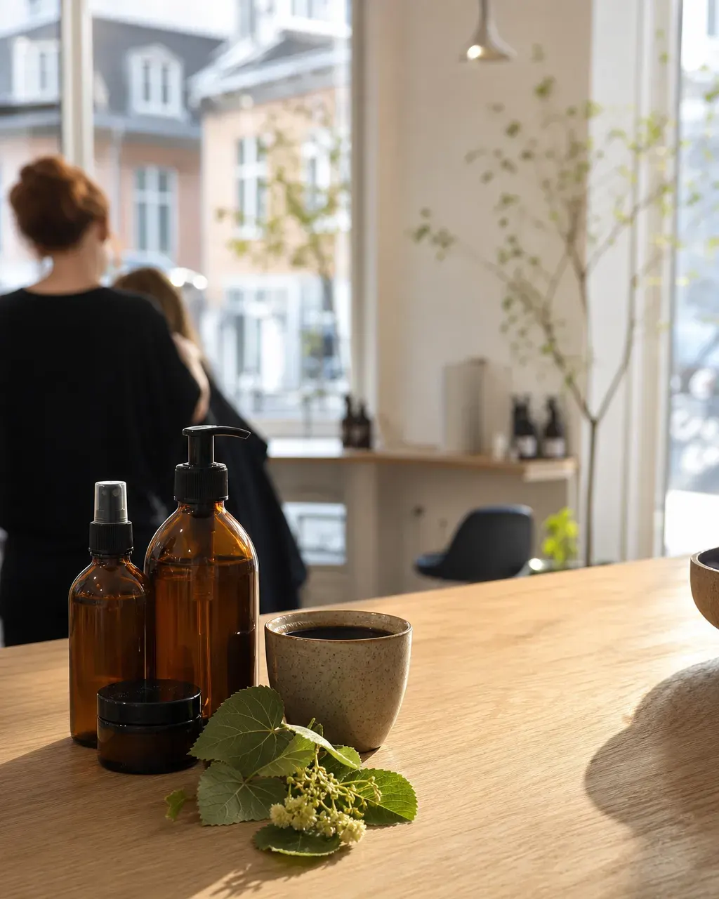 Økologiske hårprodukter i brune glasflasker ved siden af en kop kaffe på et bord af lyst træ